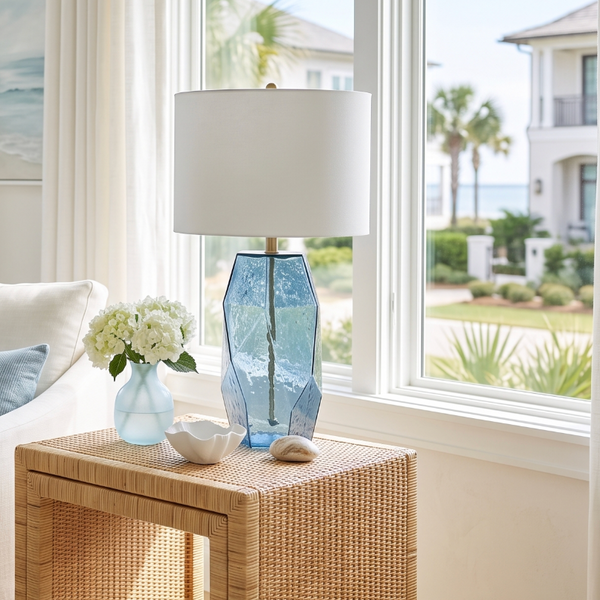 Coastal blue glass table lamp with brass hardware and a crisp white fabric drum shade.