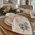 Coastal Christmas cloth napkins featuring blue-green candy canes, seashells, starfish, and evergreen foliage on an ivory background.
