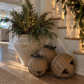 Handwoven rattan bell decorations styled with evergreen garland on a coastal Christmas fireplace mantel.