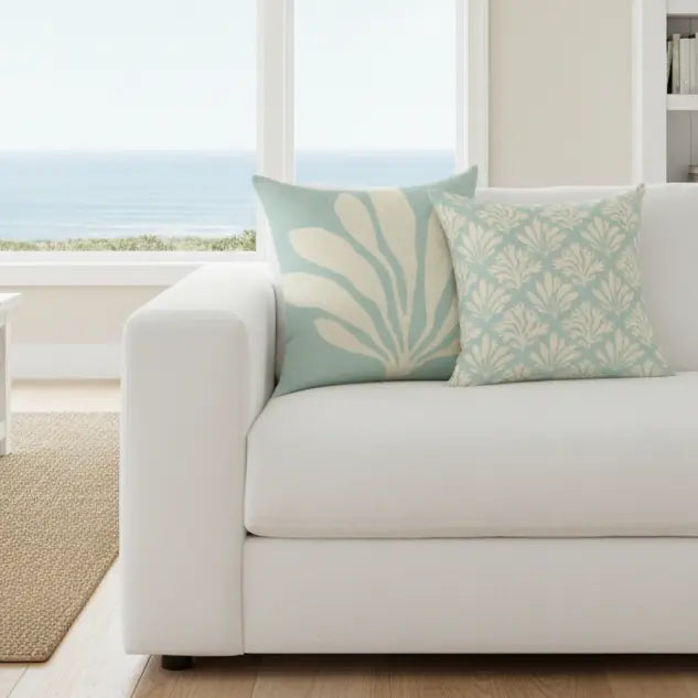 Islamorada Coral Double-Sided Throw Pillow on a white sofa, seafoam with coral-patterned front and back.