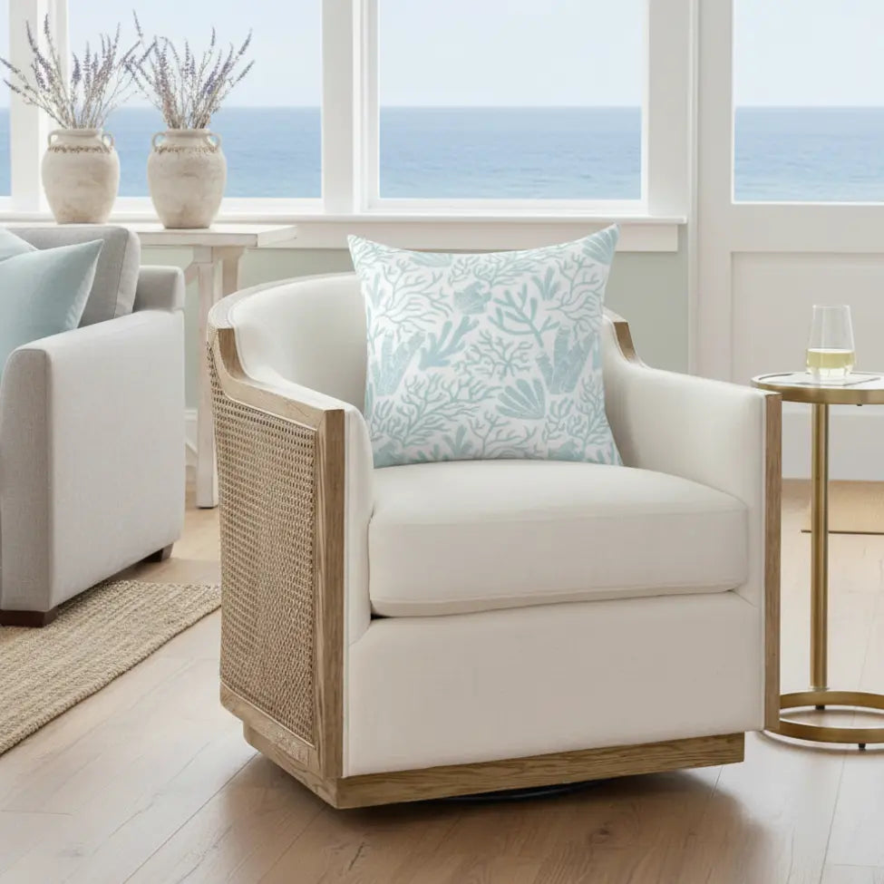 Coral Gardens Throw Pillow with aqua coastal reef pattern on a white armchair in a coastal living room.