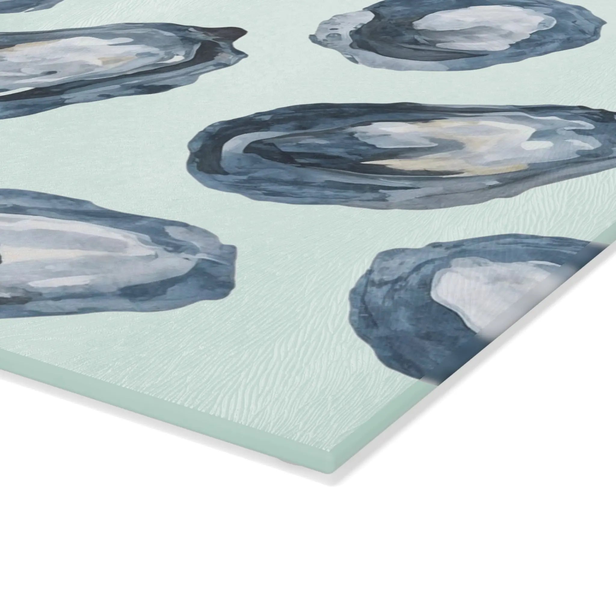 Oyster-pattern tempered glass cutting and serving board with blue oyster motifs on a pale sea-green surface.