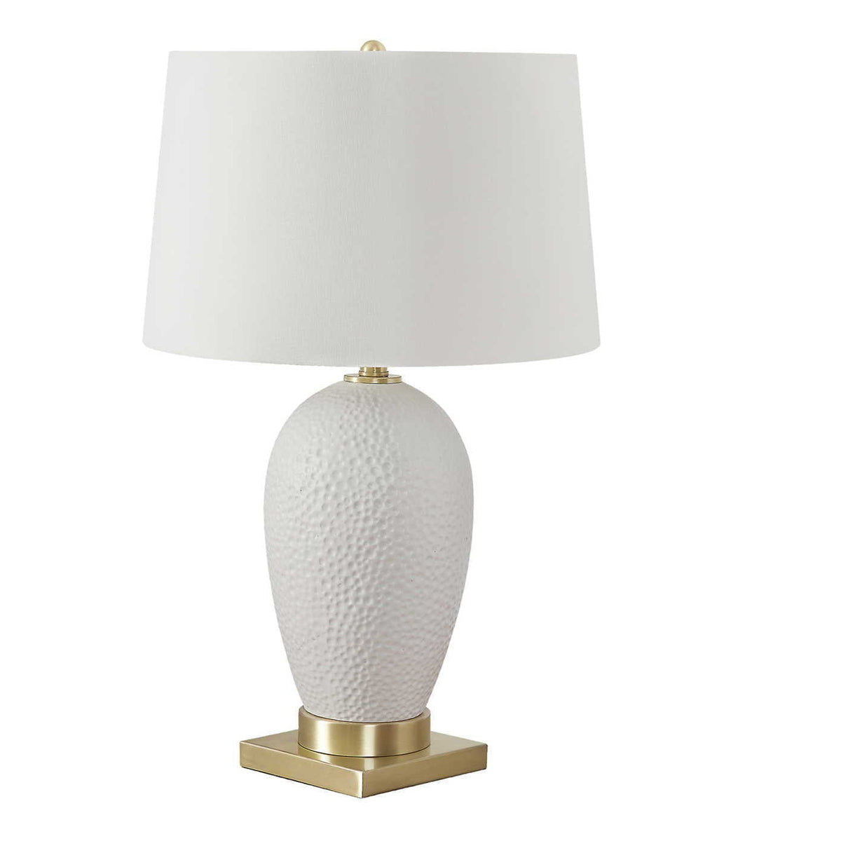 Oval-shaped white ceramic lamp base with antique brass foot and neutral linen shade for transitional or coastal interiors