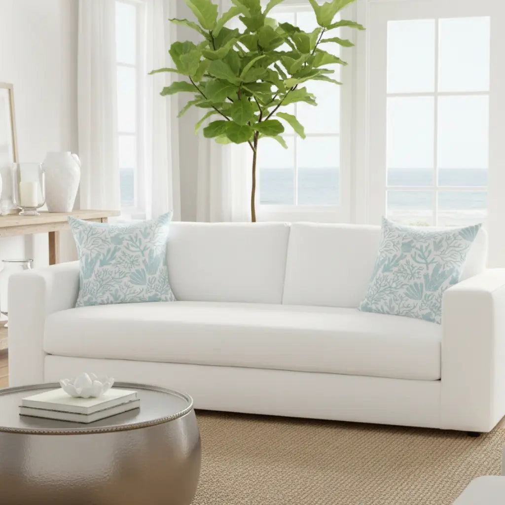 Coral Gardens Throw Pillow with aqua coastal reef pattern on a white sofa