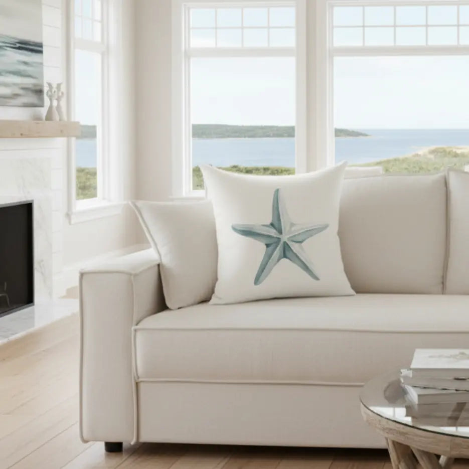Driftstar Throw Pillow with a blue starfish, coastal vibe, double-sided print on white sofa.