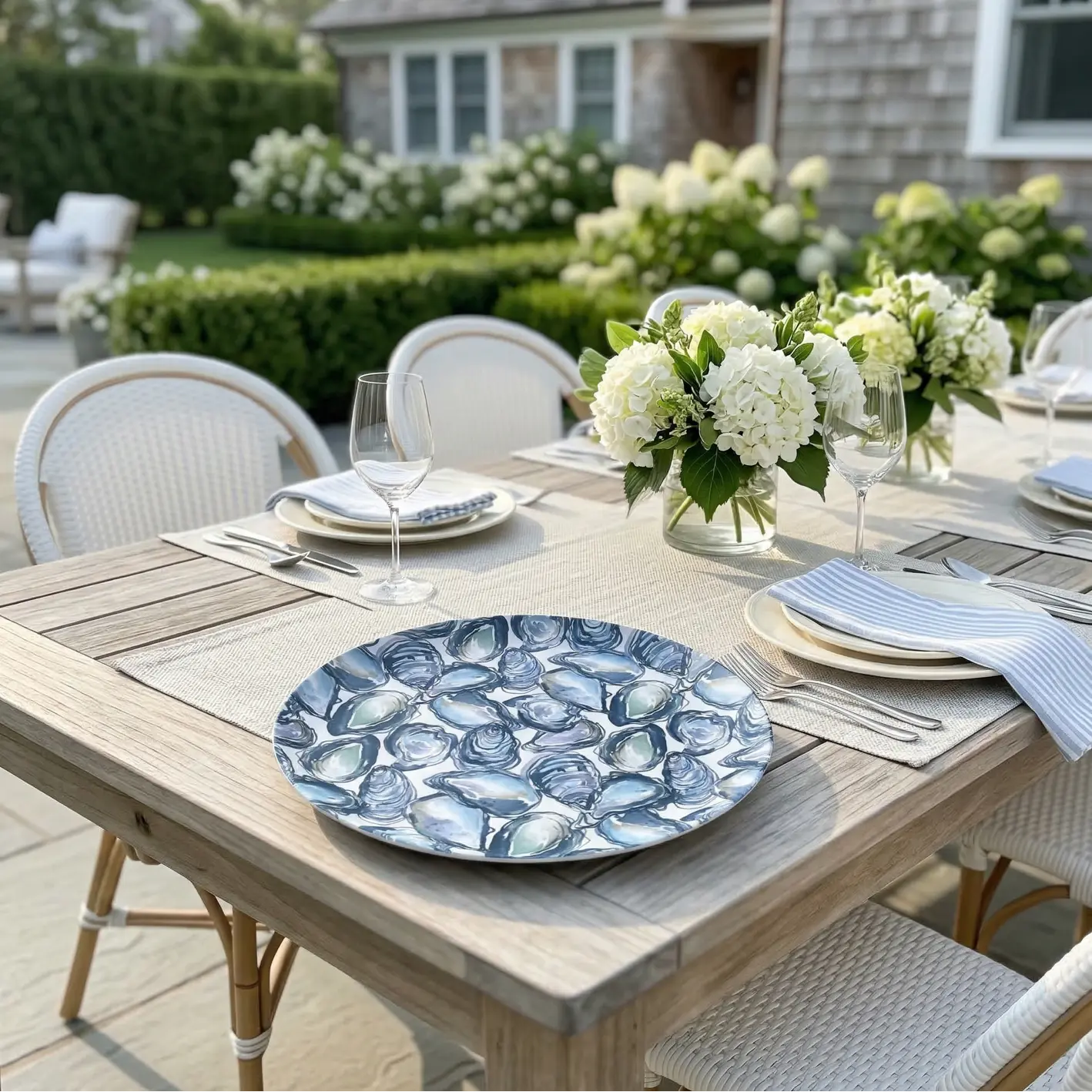 Oyster Serving Tray with a blue shell pattern on an outdoor dining table, surrounded by white hydrangea centerpieces.