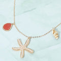 Coastal pearl pave starfish conch shell pendant charm necklace shown as beach inspired jewelry.