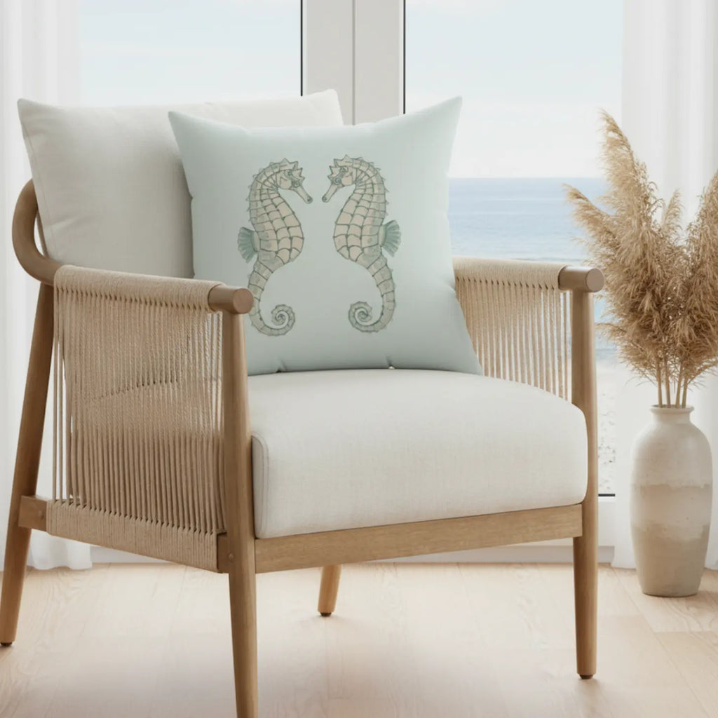 Twin Seahorse Throw Pillow: pale aqua cushion with two seahorses on a light wooden chair.