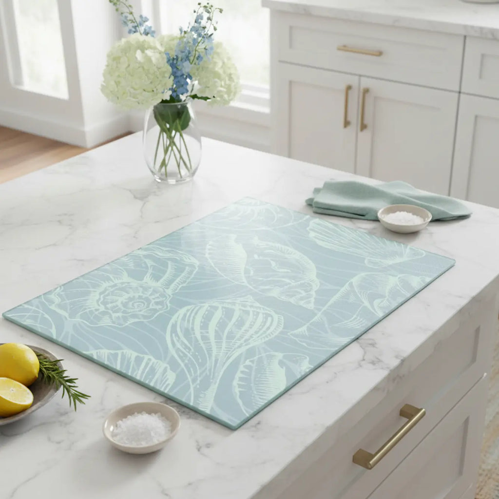 Coastal Seashell Glass Cutting Board in seafoam on marble kitchen island.