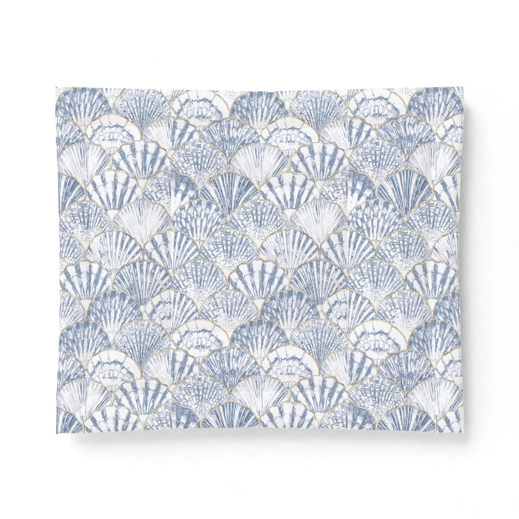 Blue and white seashell comforter adding a nautical pattern to a bright seaside bedroom