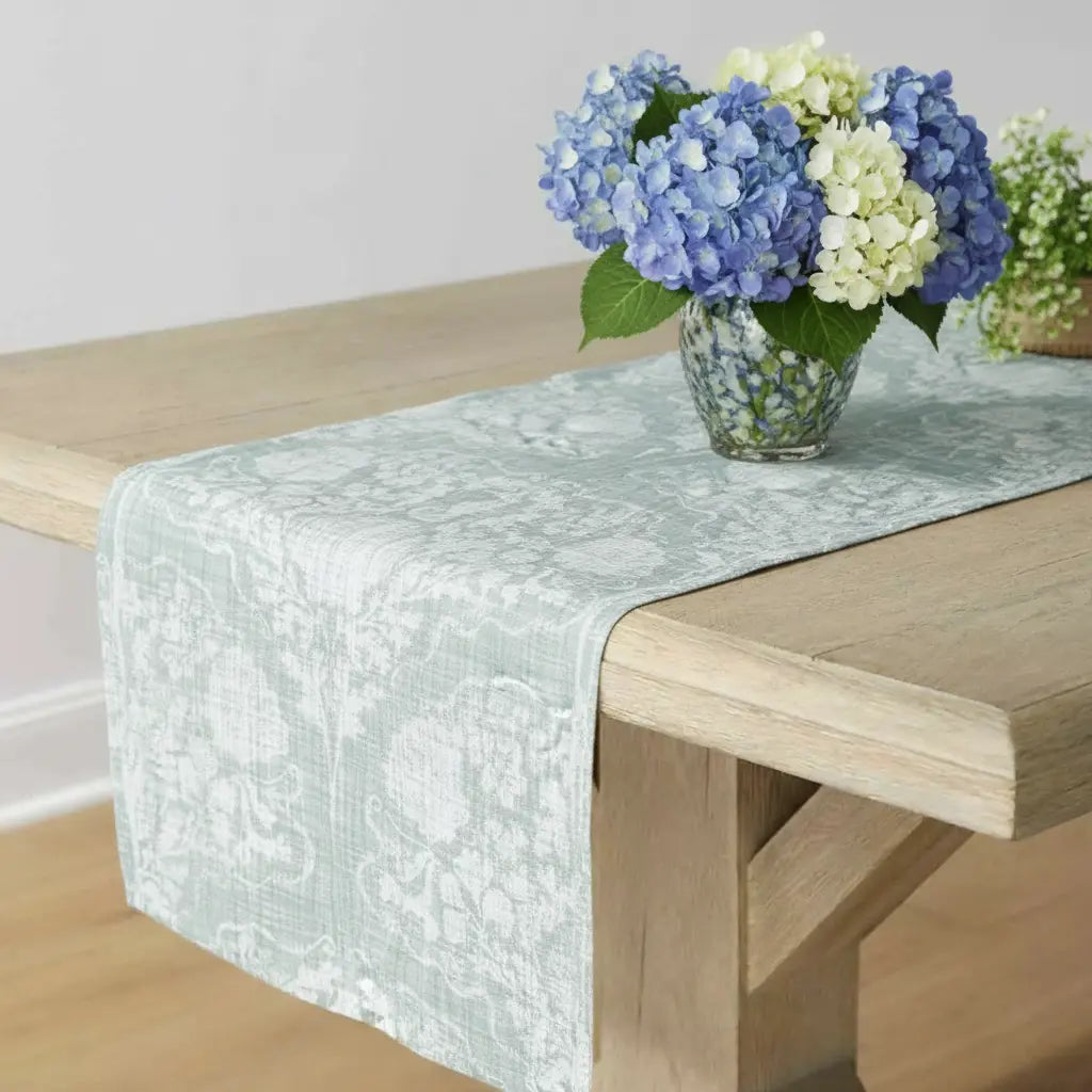 Coastal Crest Seahorse Table Runner in sage-seafoam damask on a wooden table with blue hydrangea centerpiece.