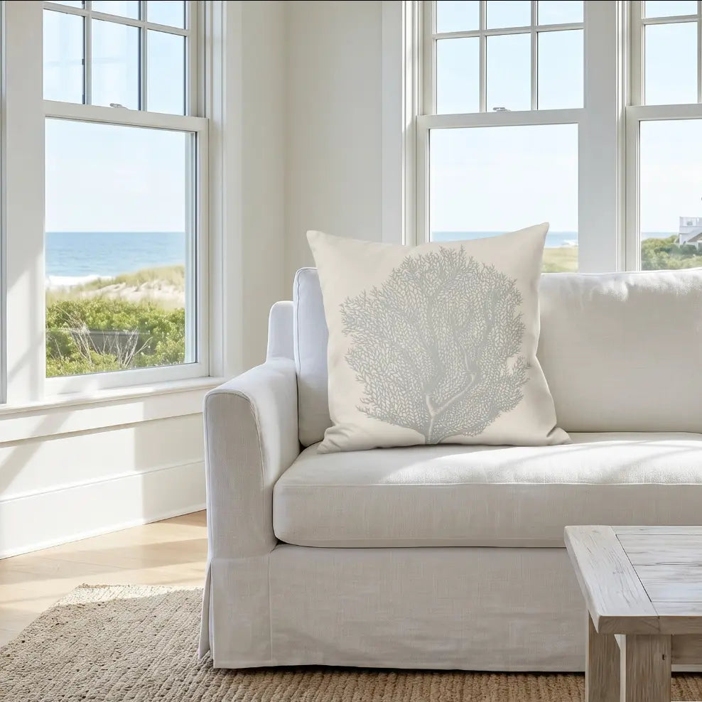 Coral coastal throw pillow on a neutral sofa in a beach house living room.