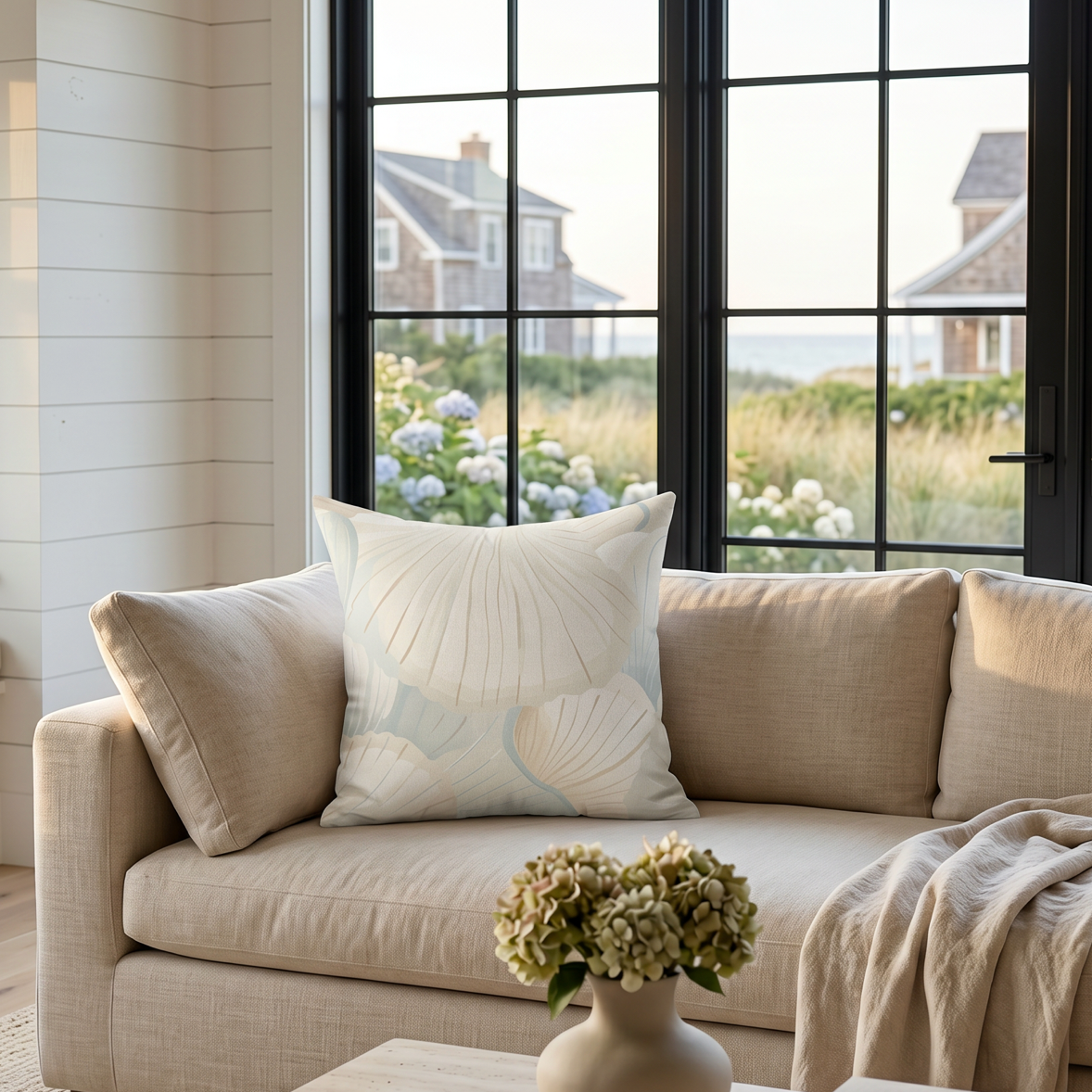 Cream seafoam shell pattern pillow on a couch in a beach house style living room