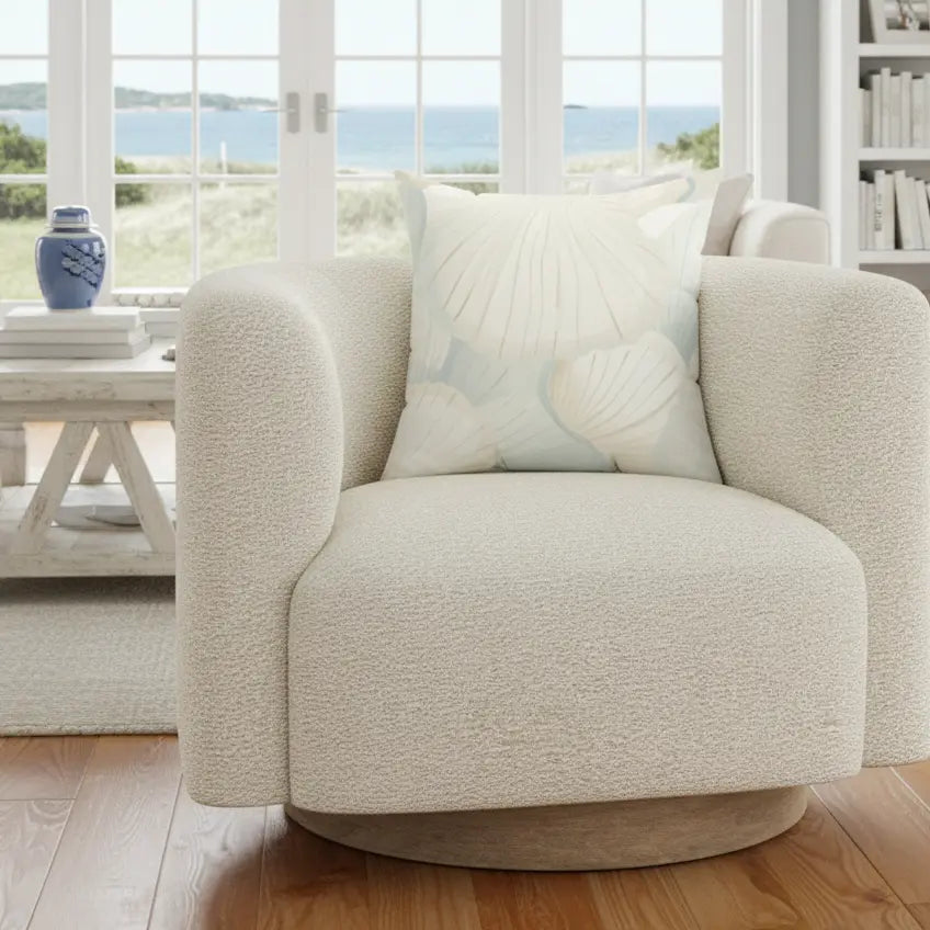 Cream seafoam shell pattern pillow on a couch in a beach house style living room.