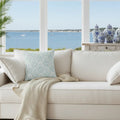Valencia Damask Throw Pillow with soft aqua pattern on white sofa beside coastal decor.