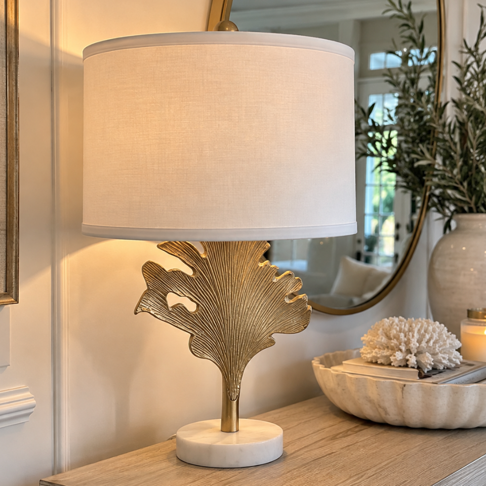 Sculptural gold leaf table lamp styled on a coastal living room side table beside a neutral sofa.