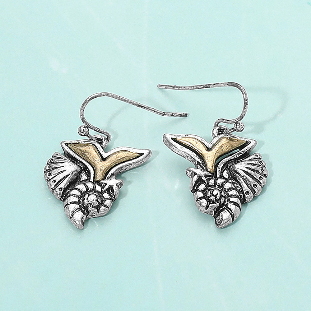 Coastal gold whale tail starfish and conch shell charm dangle earrings shown as beach inspired jewelry.
