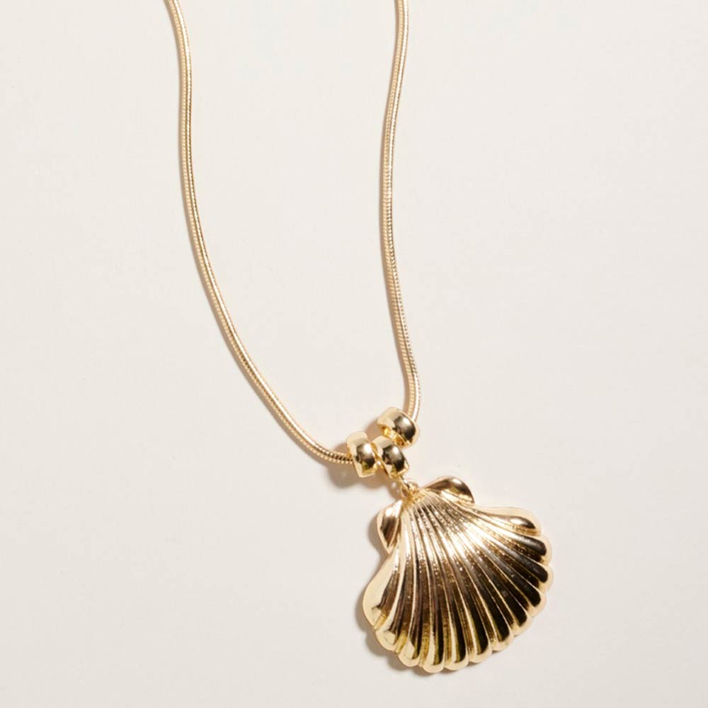 Gold seashell necklace used as minimal beach jewelry in a coastal inspired outfit