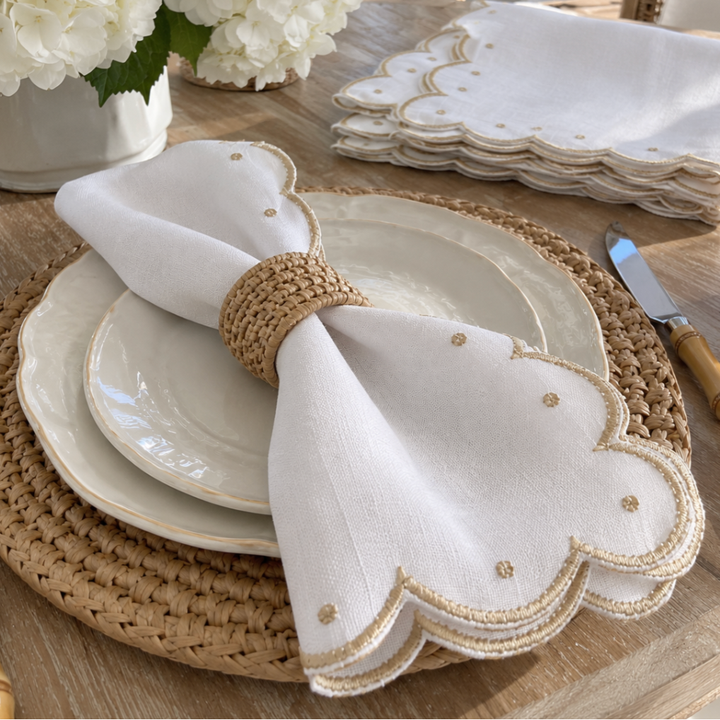 White scalloped napkins with elegant gold trim and embroidered accents.
