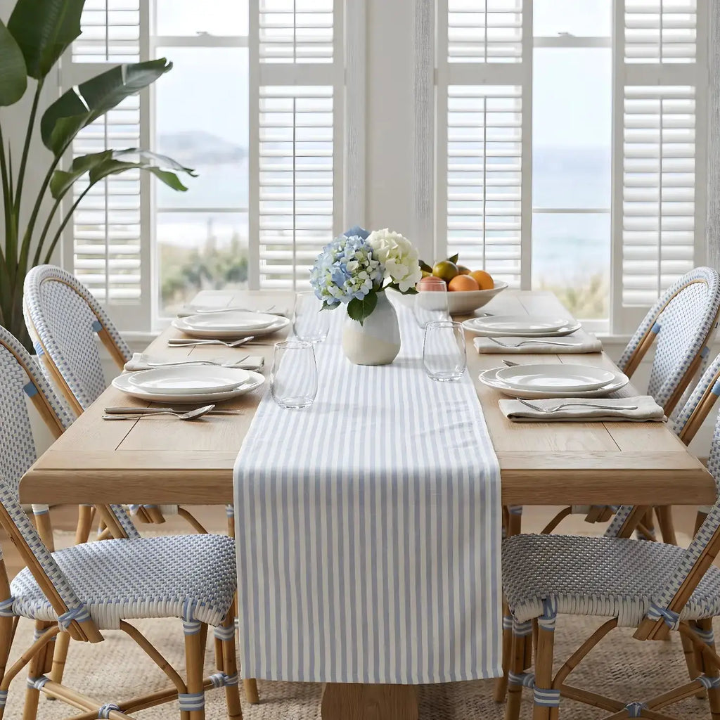 Gray and white stripe table runner on a modern coastal dining table with white dinnerware