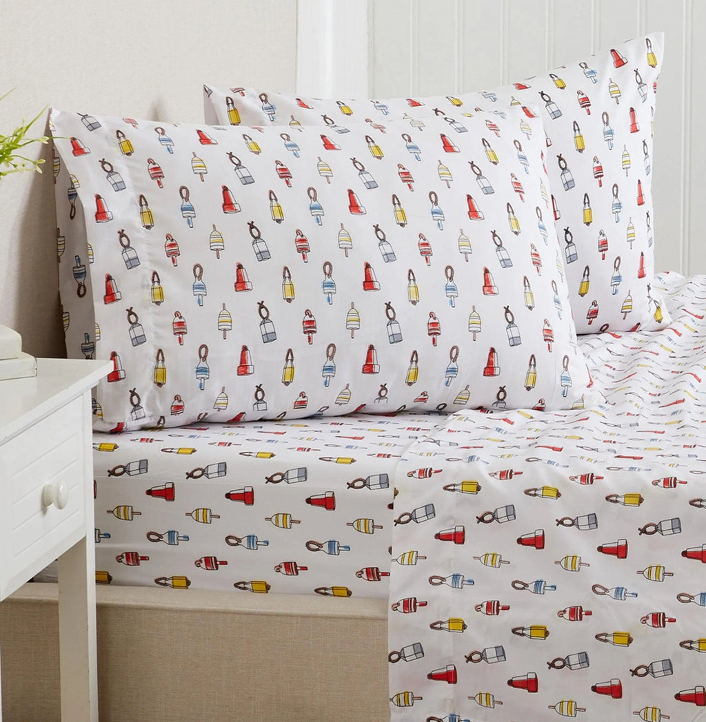Coastal sheet set with nautical buoy print on white, two pillowcases visible