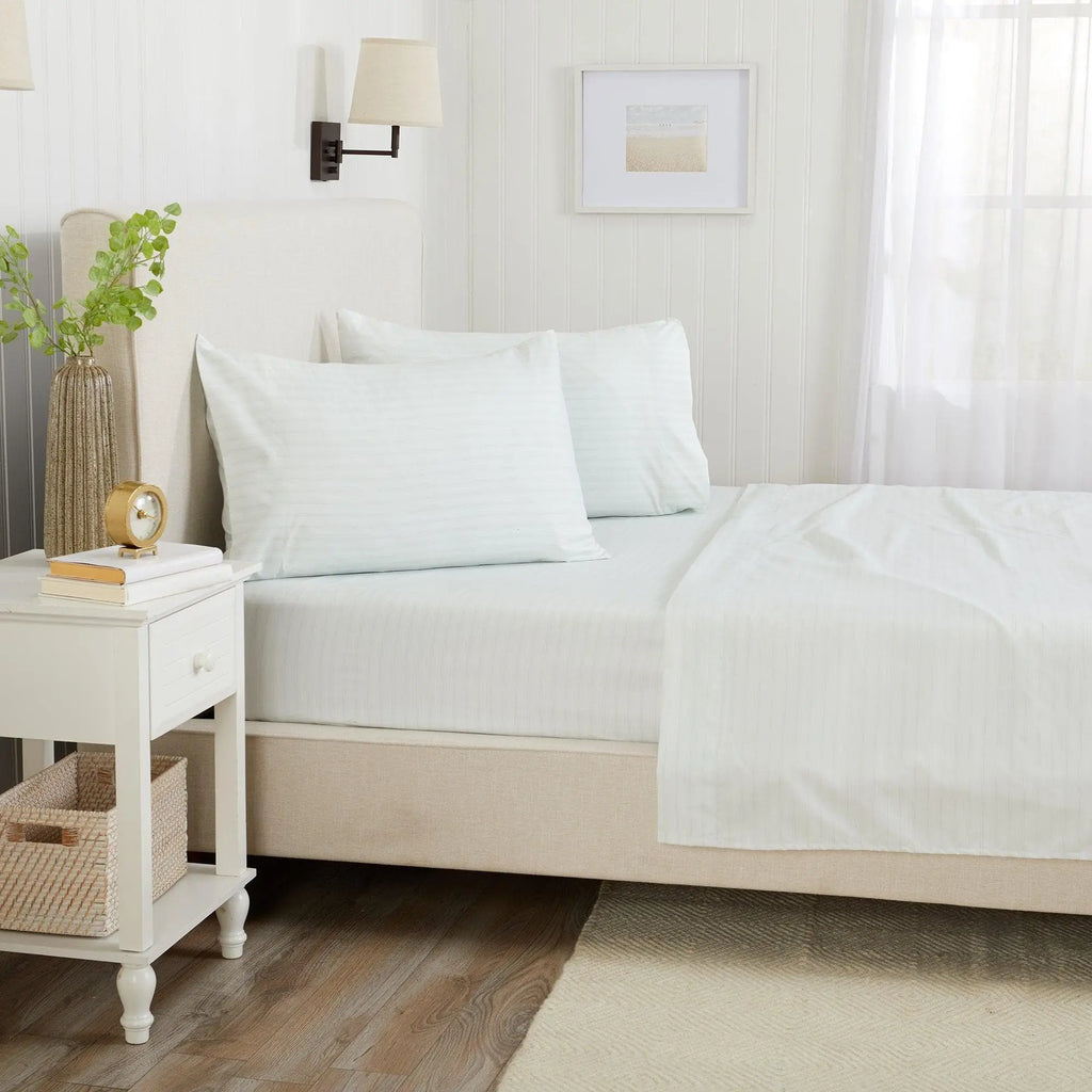 Great Bay Home Stripe Sheet Set, Adeline Collection, on a bed with white striped sheets and pale blue pillows.