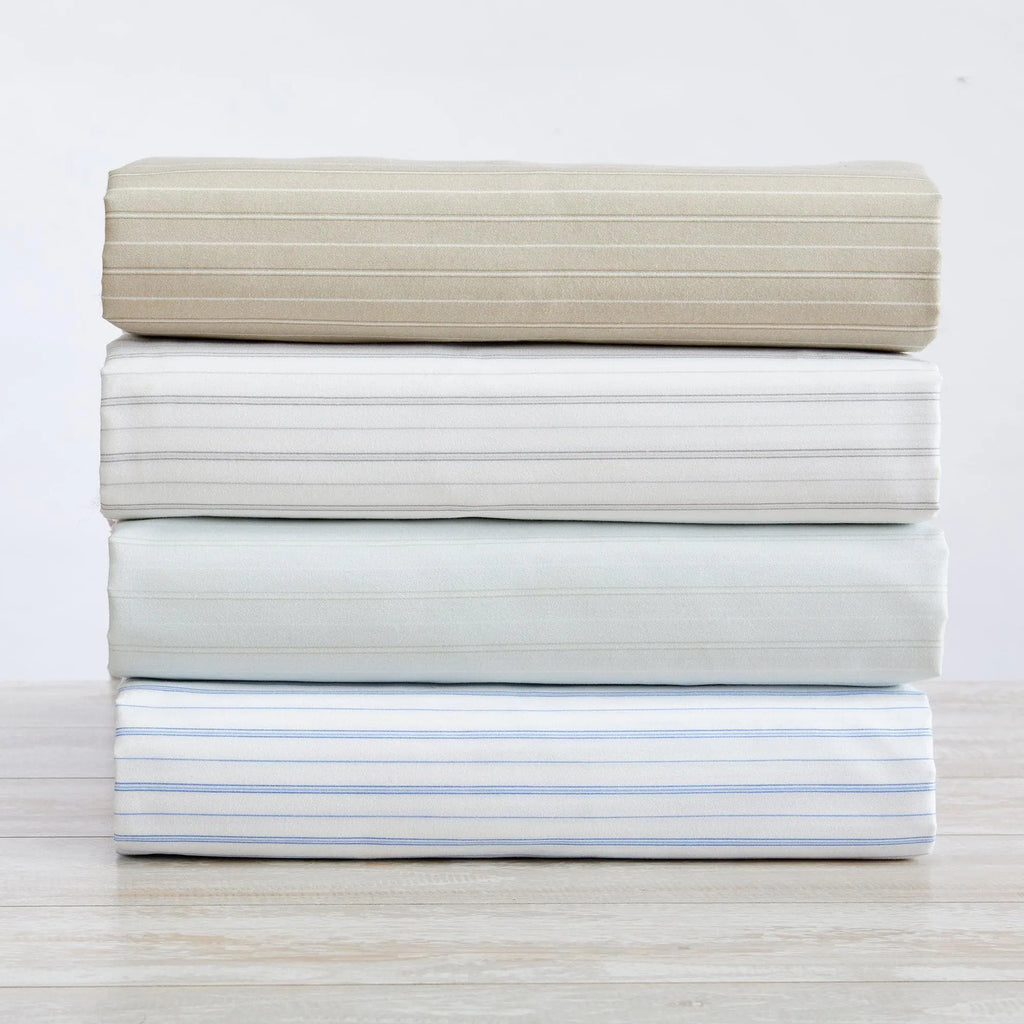 Stripe Sheet Set Adeline Collection Great Bay Home; four folded striped bed sheets in beige, white, gray, and blue.