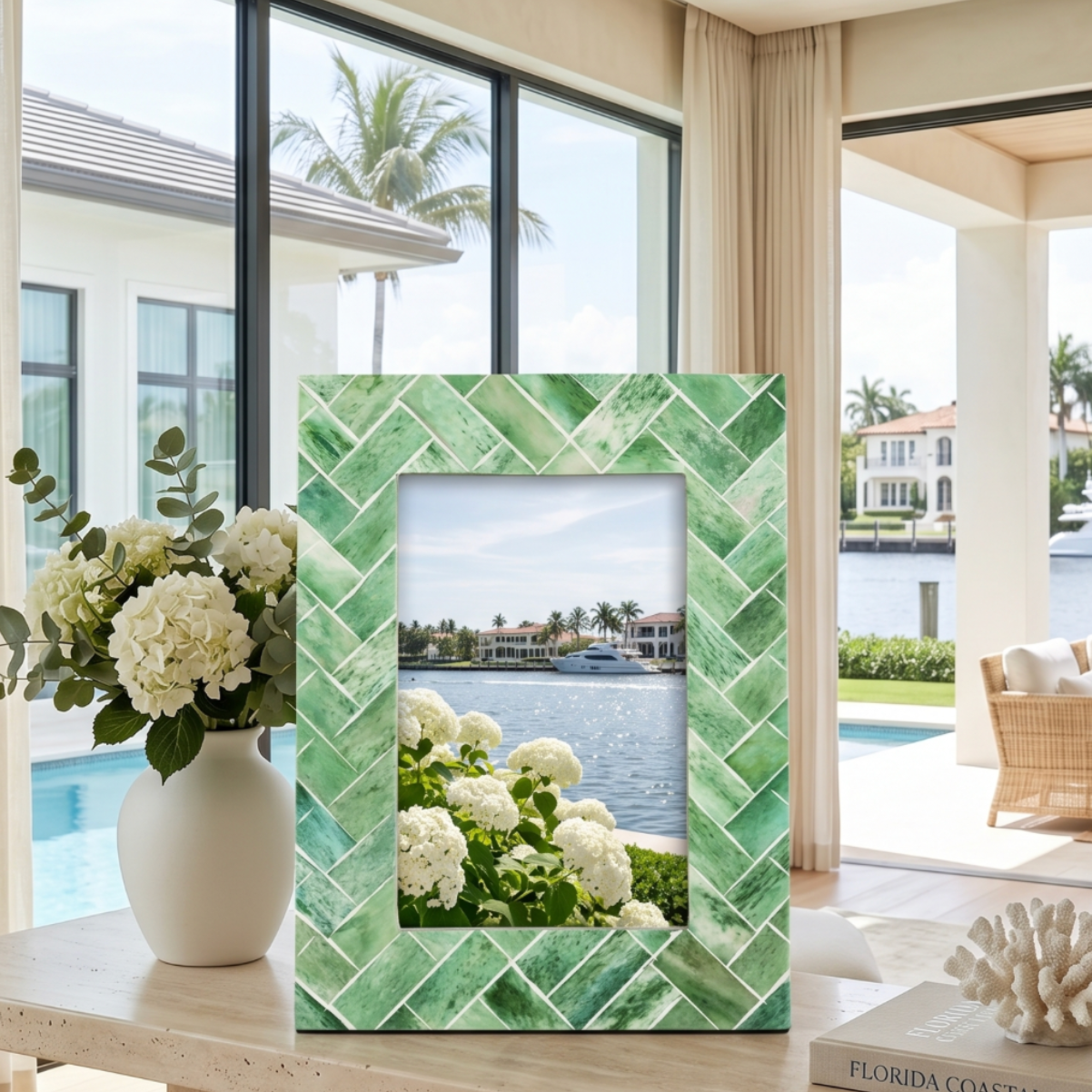 Green tropical palm leaf picture frame holding a 4x6 photo styled on a coastal console table