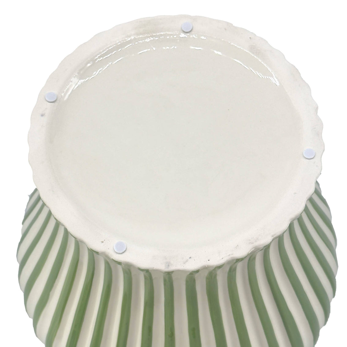 Green and white striped lidded vase complementing neutral home furnishings and natural textures.