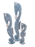 Three hand-carved coastal wood seahorses in ocean blue and teal tones.