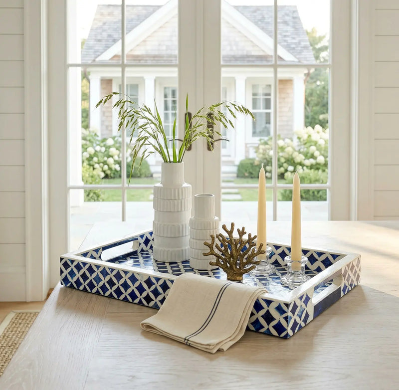 Console table styled with coastal bowls, coral, books, and lamp