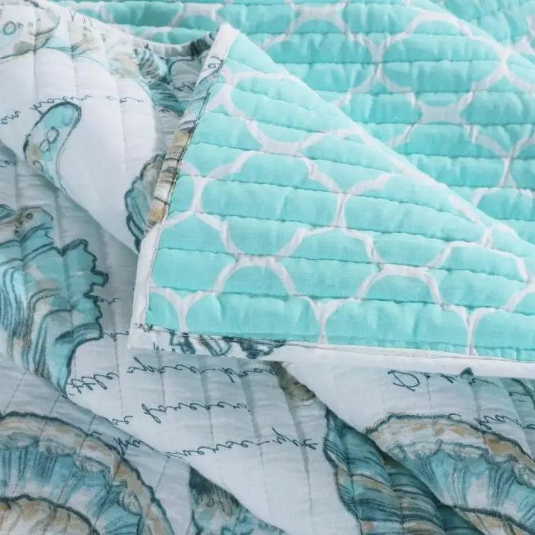 Closeup of king coastal seashells quilt set showing white and teal seashell pattern