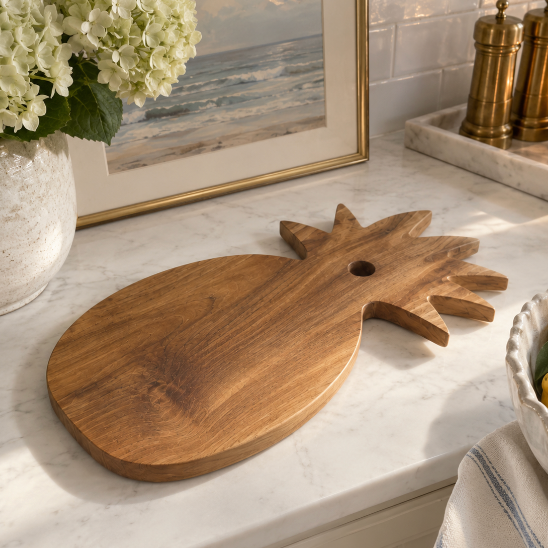 Large solid teak pineapple cutting board with warm golden-brown wood grain and a convenient hanging hole.