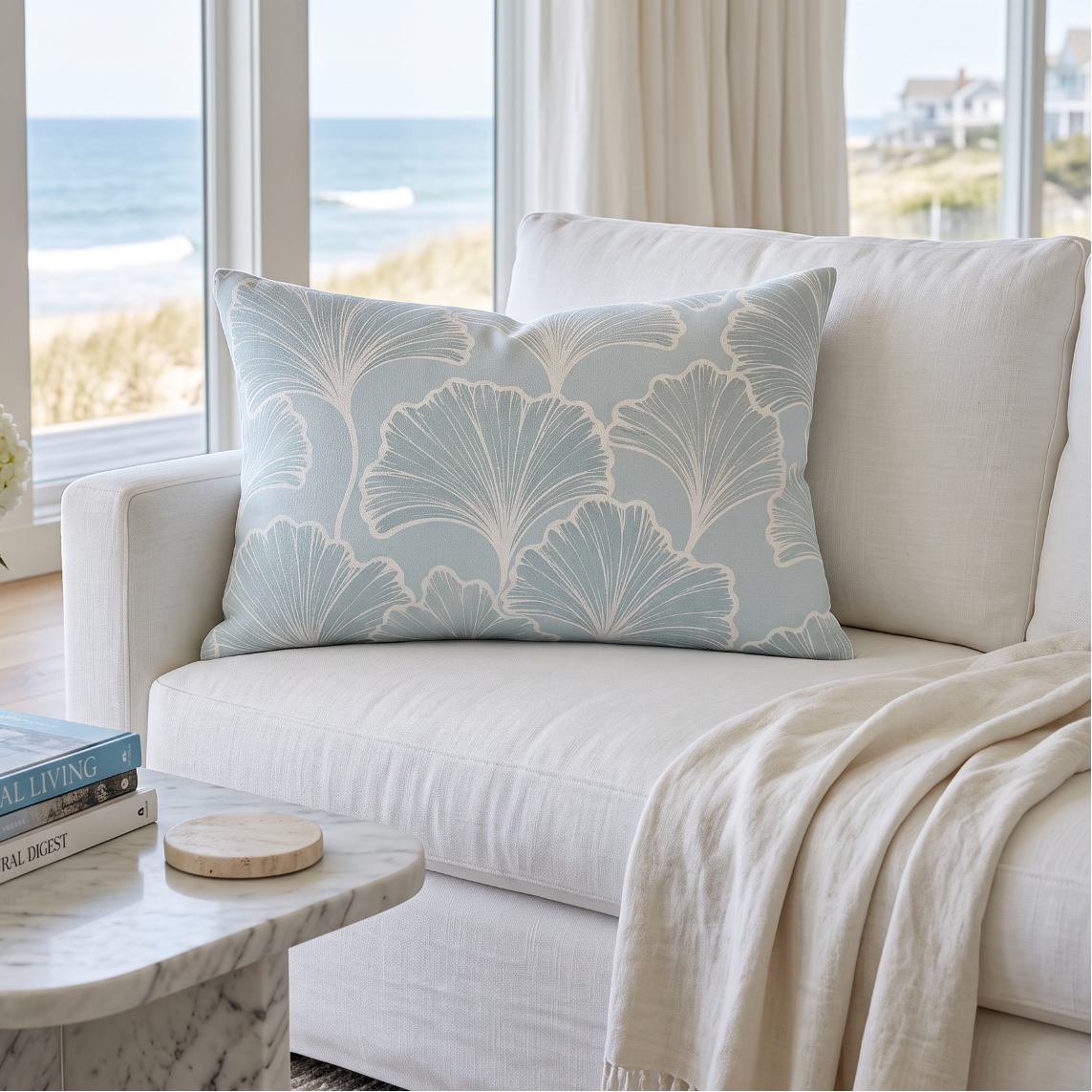 Light blue coastal botanical lumbar pillow with white leaf pattern styled on a neutral sofa in an ocean‑view living room