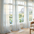 Ocean coral light blue semi sheer curtains softly filtering light in a beach house living room.
