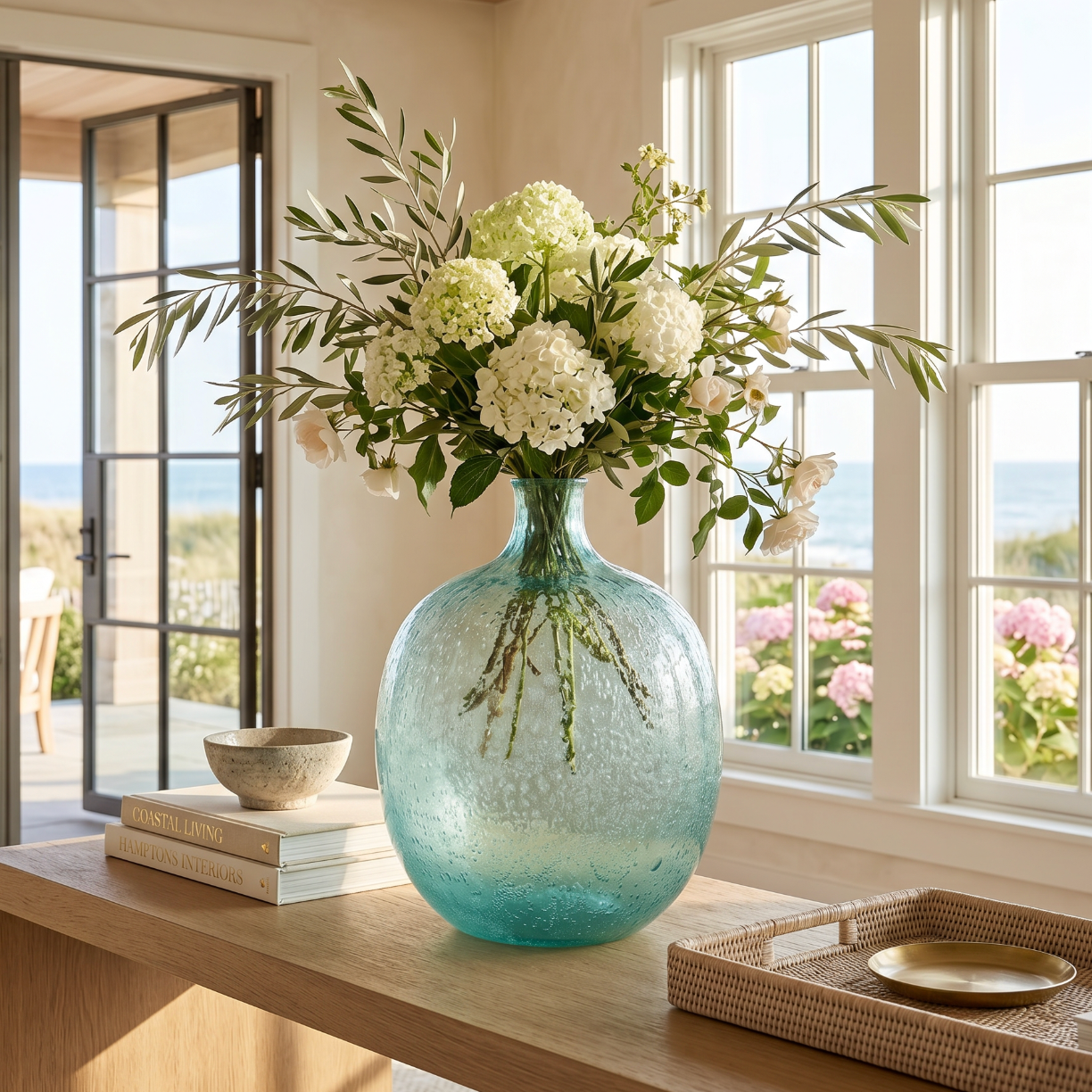 Light blue glass vase used as a coastal home decor centerpiece with fresh flowers on a dining table.