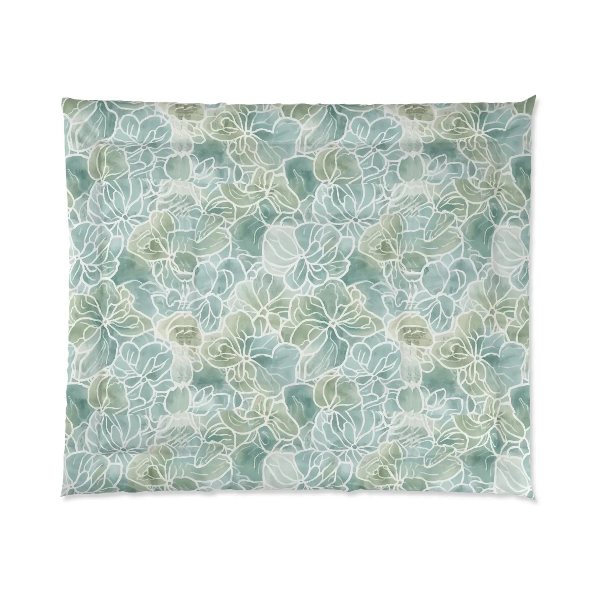 Light blue/green floral comforter set styled with white pillows in a relaxed seaside room