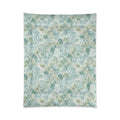 Light blue/green floral comforter layered with white pillows and a throw in a beach house guest room.
