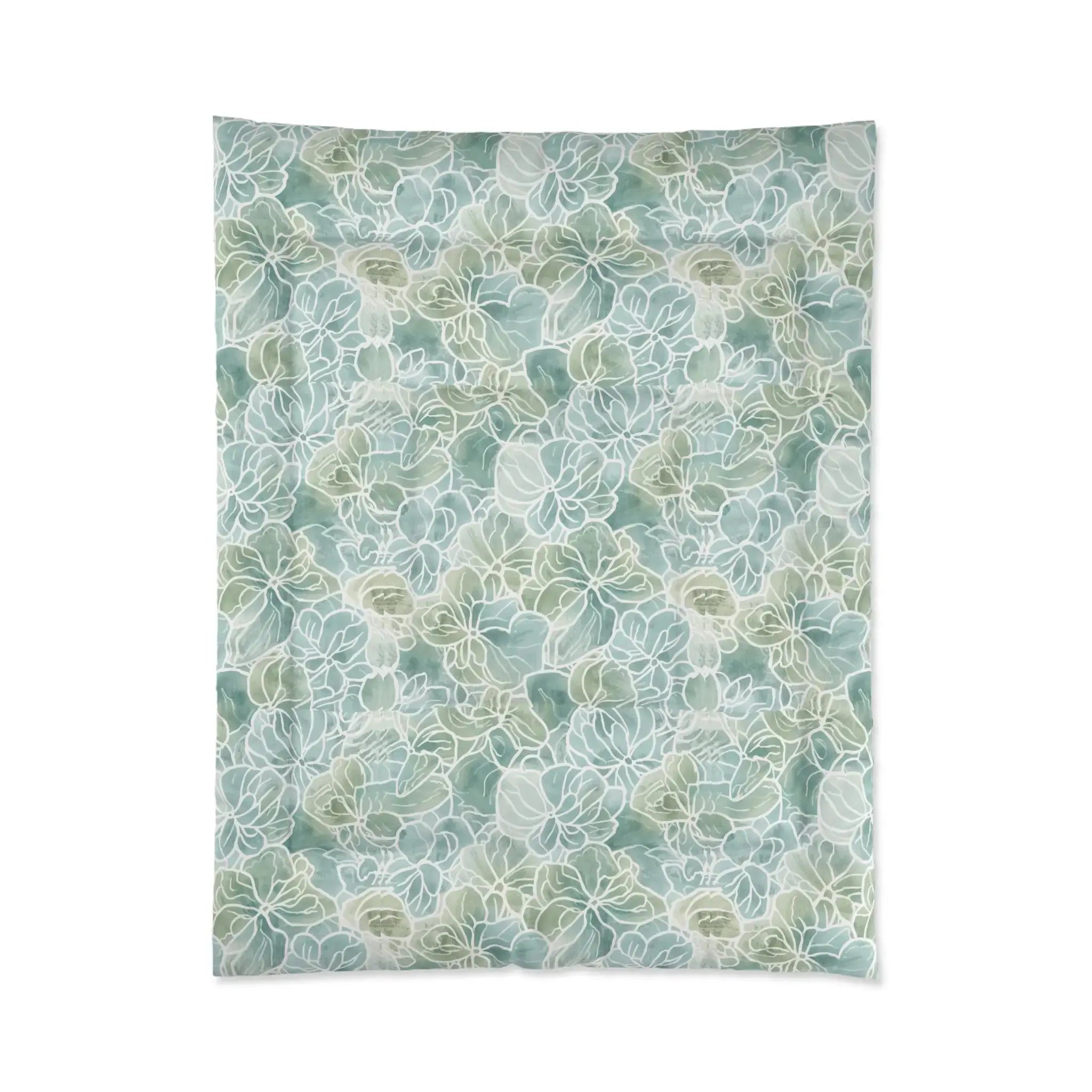 Light blue/green floral comforter layered with white pillows and a throw in a beach house guest room.