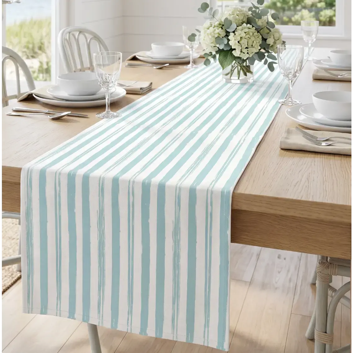 Light blue watercolor stripe table runner on a coastal dining table with simple white plates.