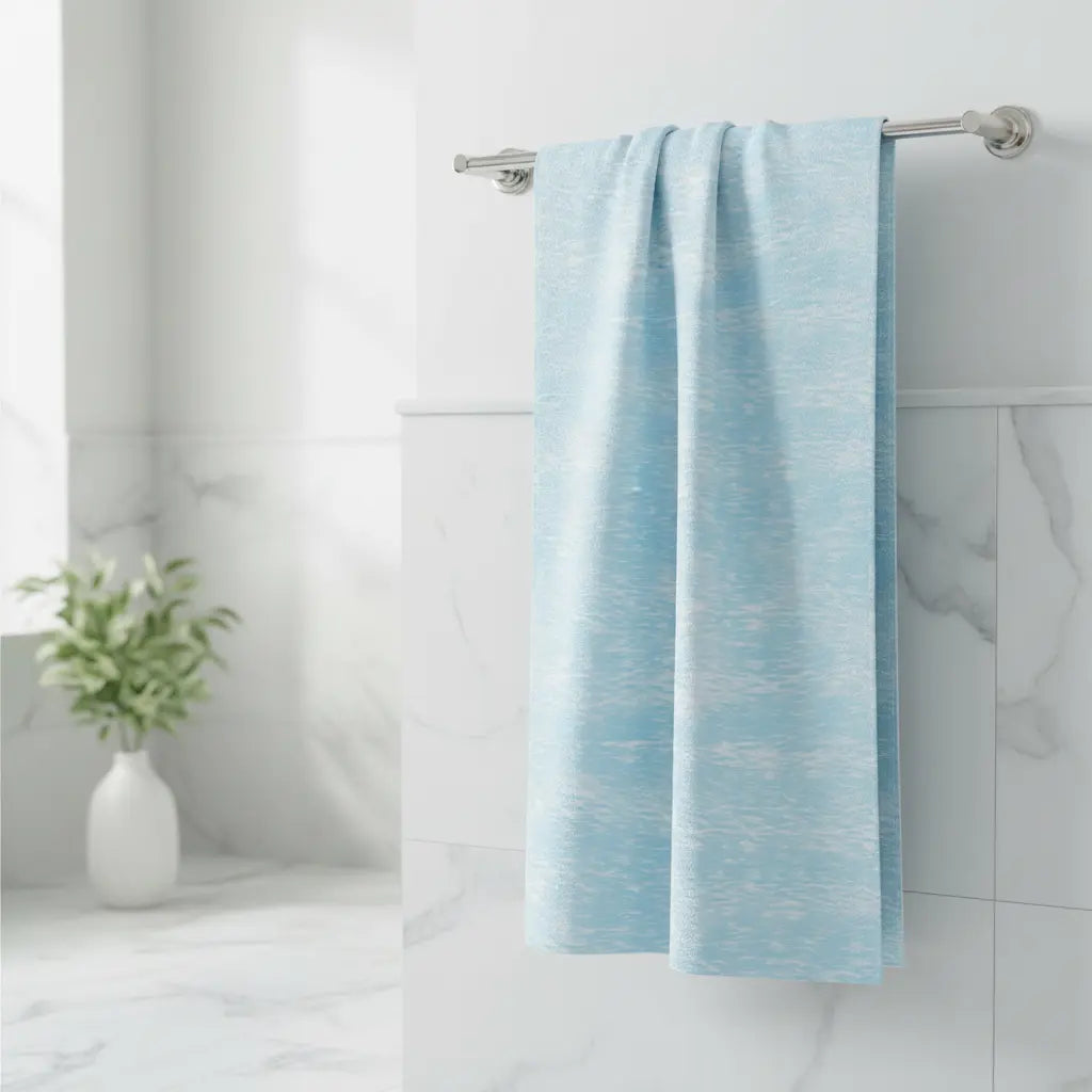 Light blue towel hanging on a rack in a bathroom with a white vase and plant.
