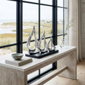 Minimalist sailboat sculpture placed on a mantel with other coastal decorative accents.