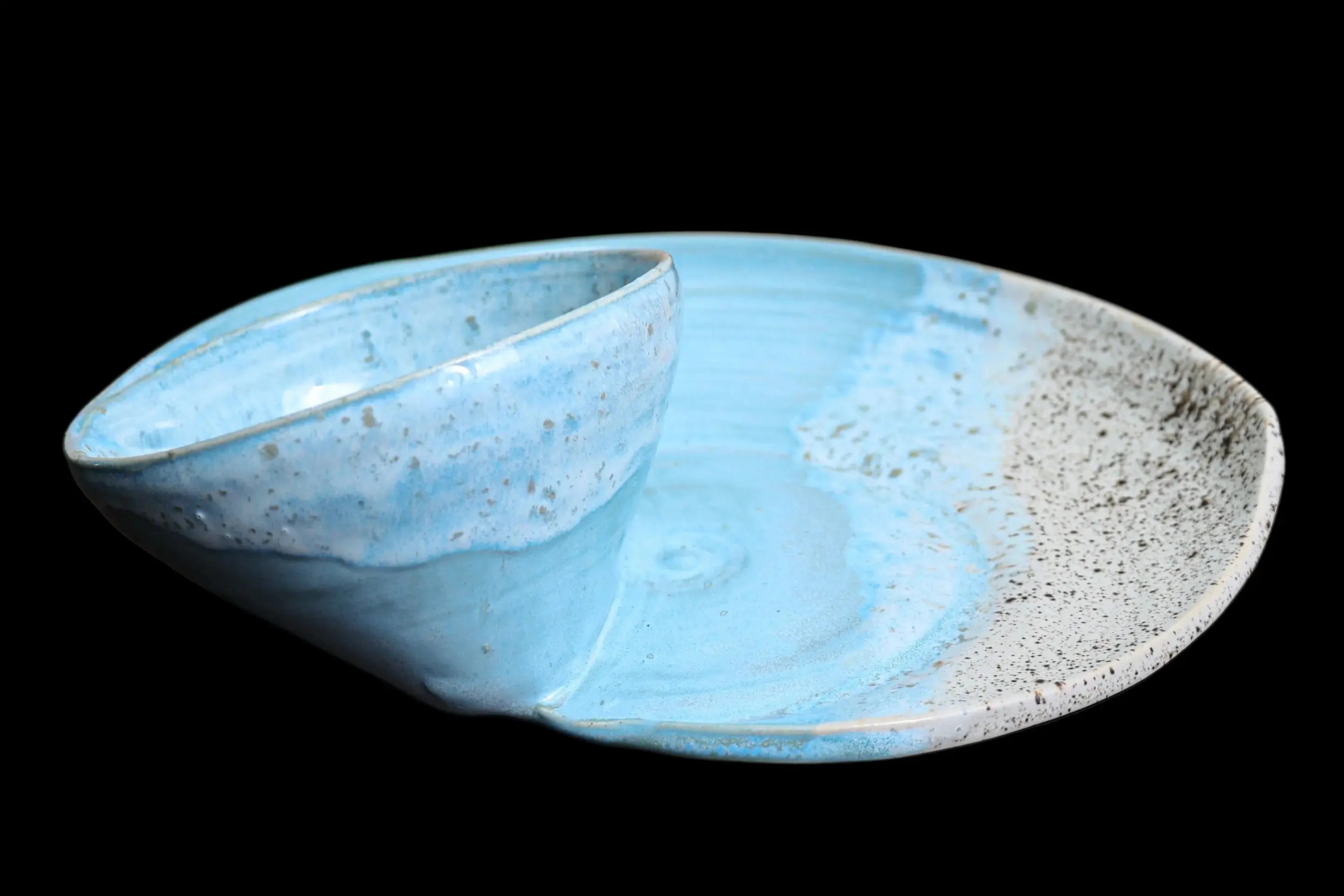 Blue handmade coastal swirly serving bowls on a matching plate with marbled glaze.