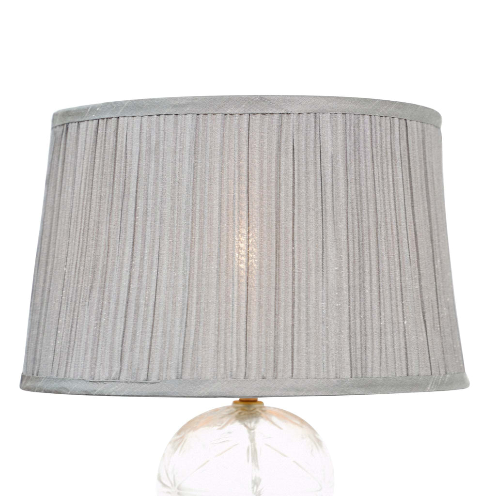 Modern table lamp featuring a clear textured glass body and elegant grey fabric shade.