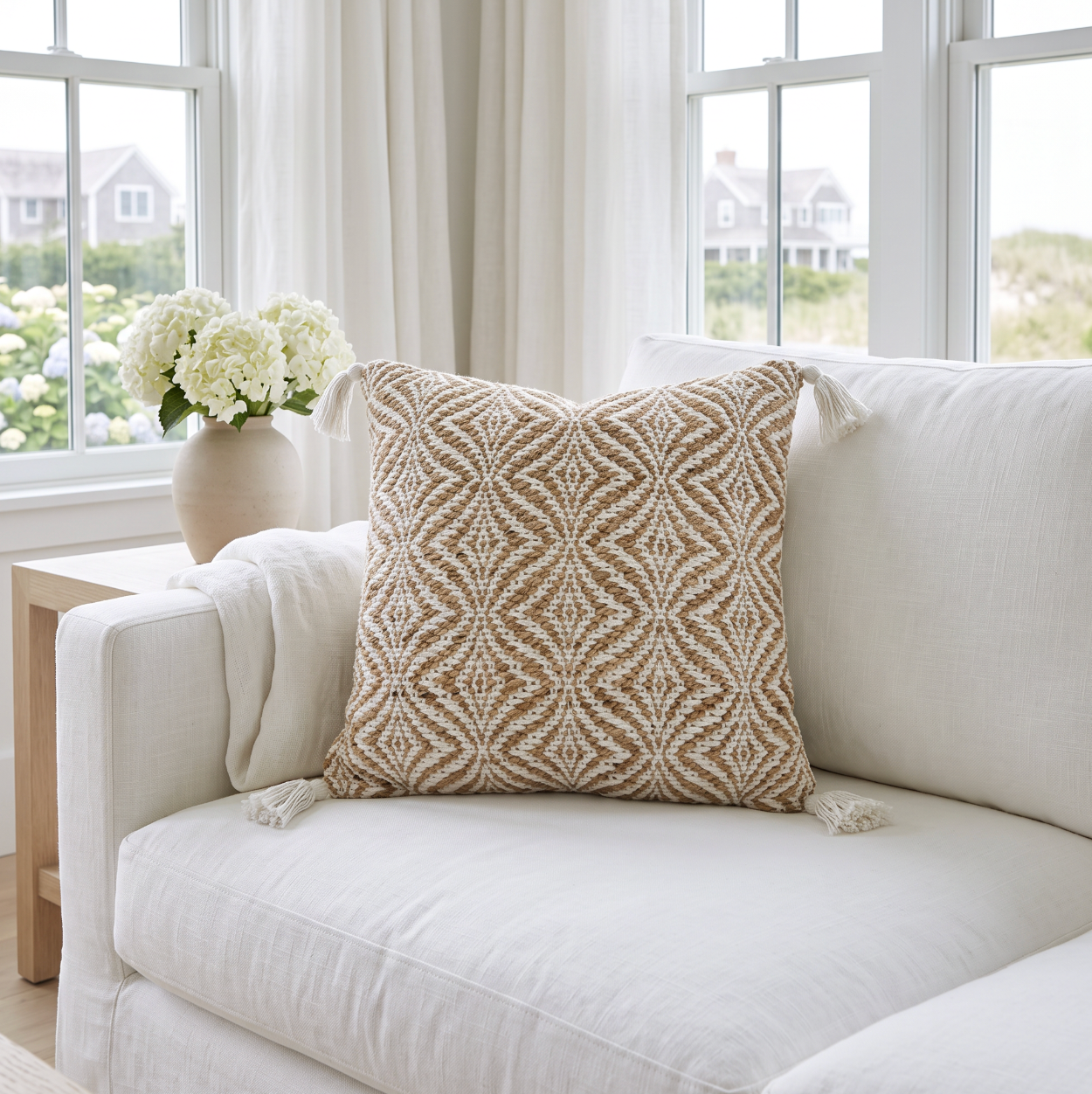Neutral 20 by 20 inch jute and cotton pillow featuring subtle wavy lines and soft tassels at each corner.
