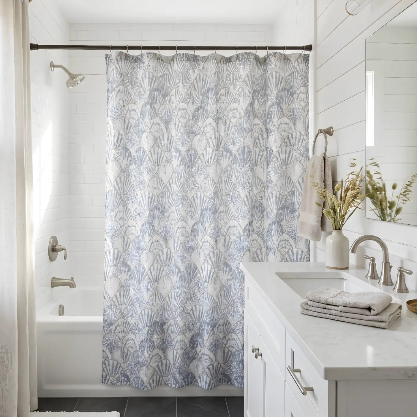 Coastal blue and white seashell print fabric shower curtain used as beach house bath decor.