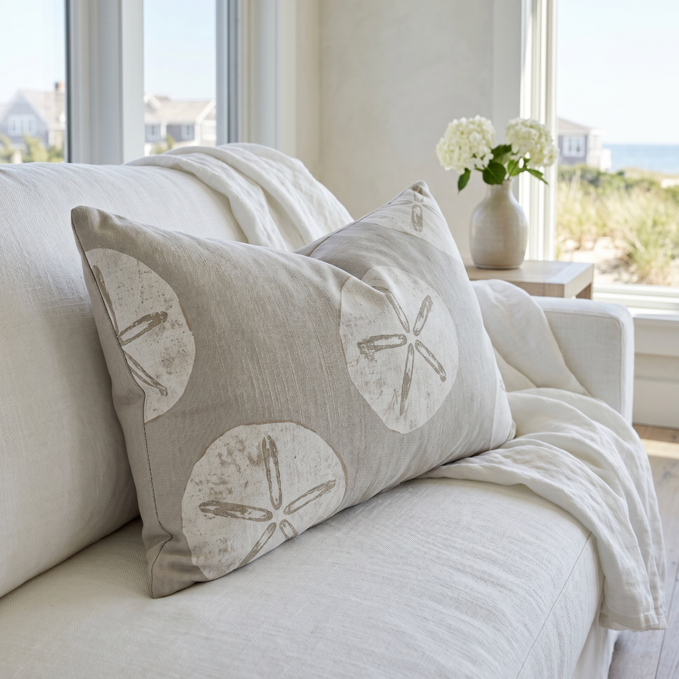 Neutral sand dollar throw pillow styled on a light sofa for coastal home décor.