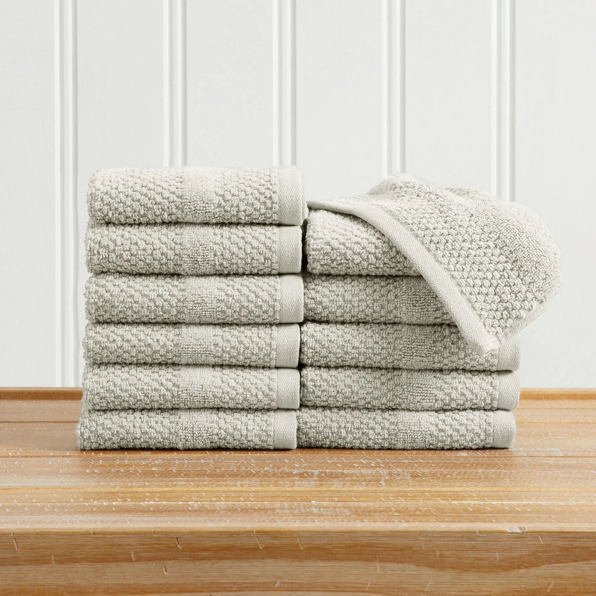 Marbella collection 100% cotton bath towel set in neutral beige, woven texture stacked on a wooden surface