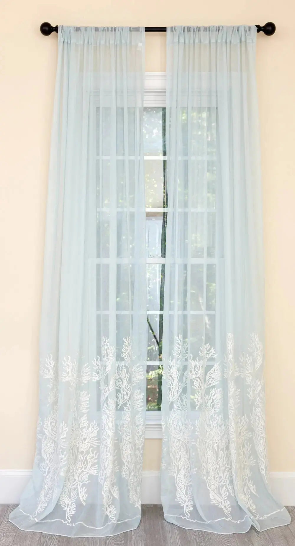 Pair of light blue coral coastal semi sheer curtains on a large window.