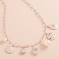 Coastal charm necklace with metal seashell and sand dollar charms, starfish accents and pearls in a station design